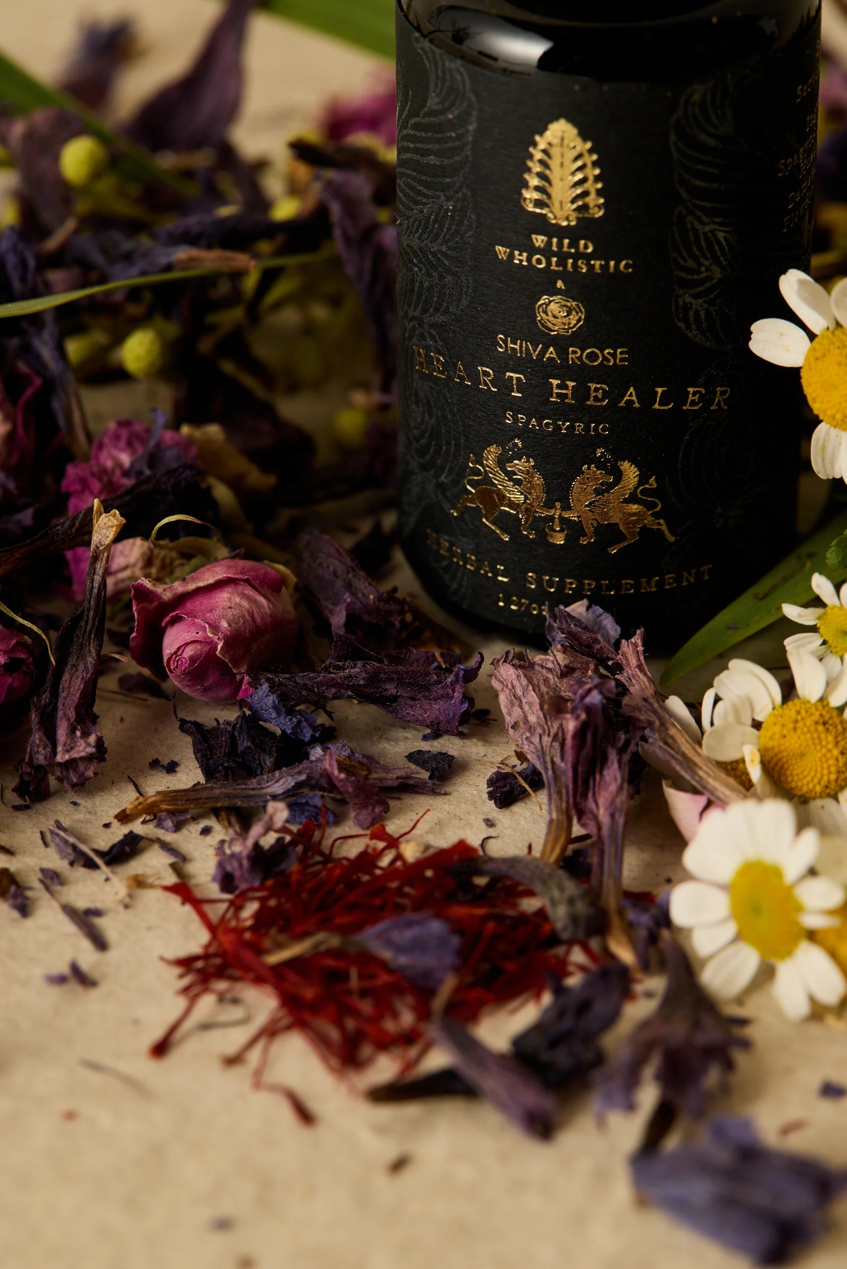 Bottle of 'Heart Healer' with dried herbs and flowers on a textured surface