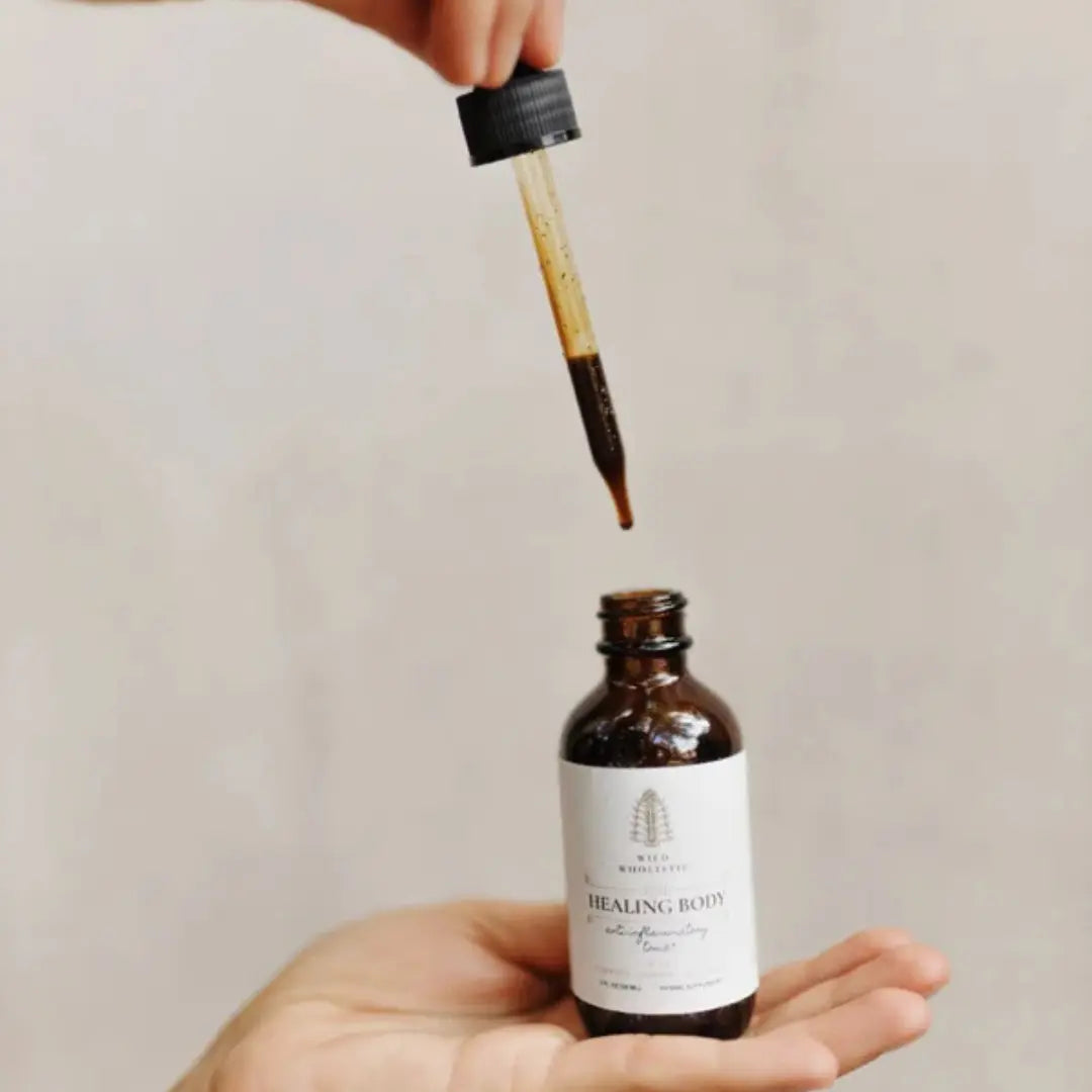 Bottle of 'Healing Body' oil with a dropper held above it against a neutral background
