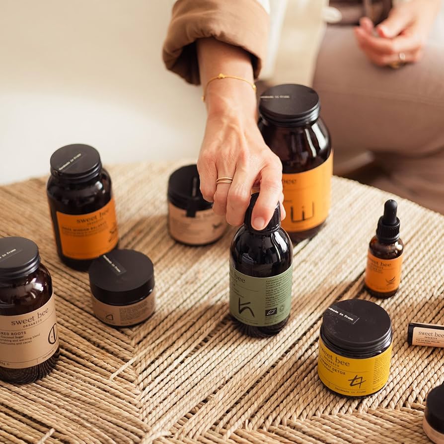 Hand reaching for a bottle among various skincare products on a textured surface