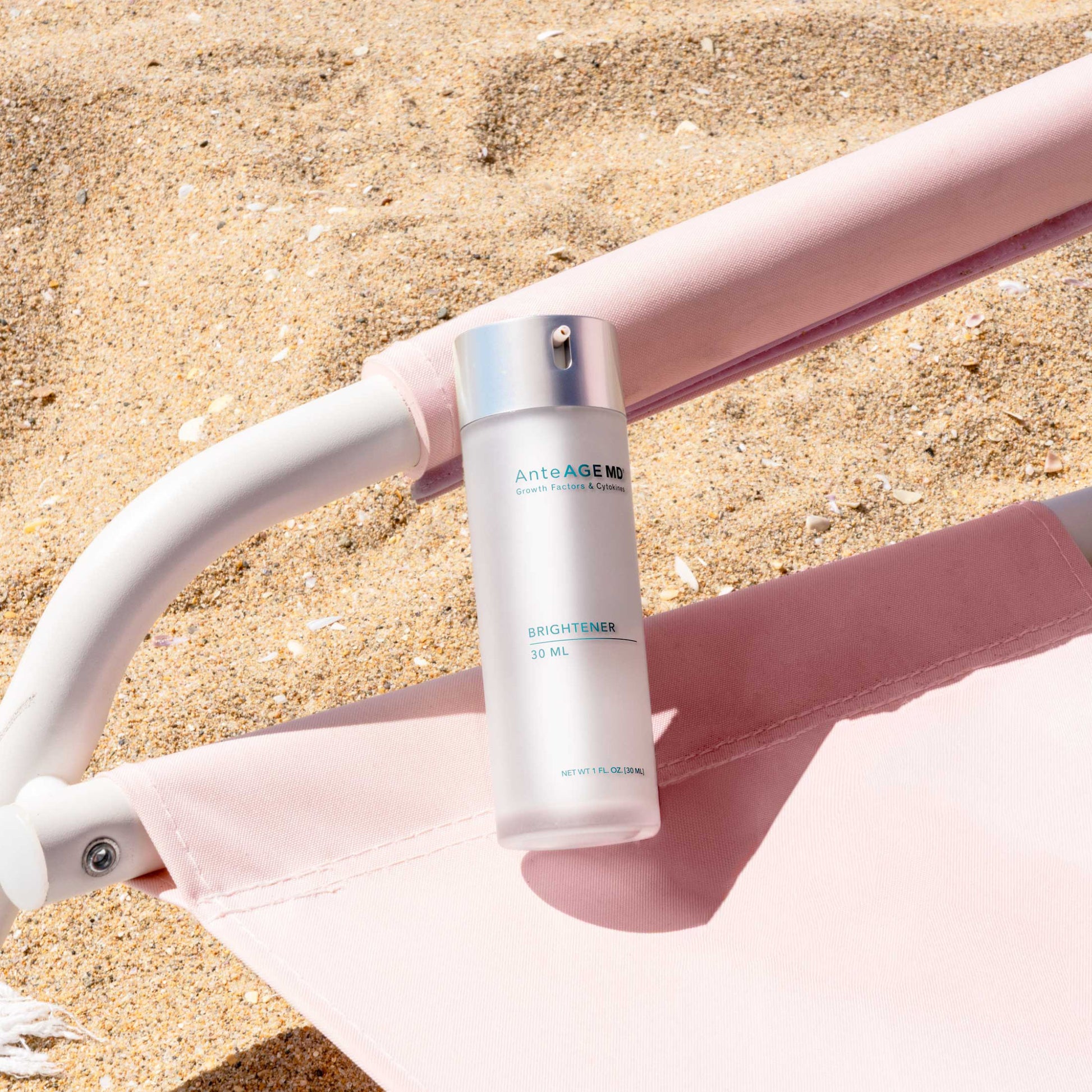 Anteage Skincare bottle on a pink beach chair with sand background