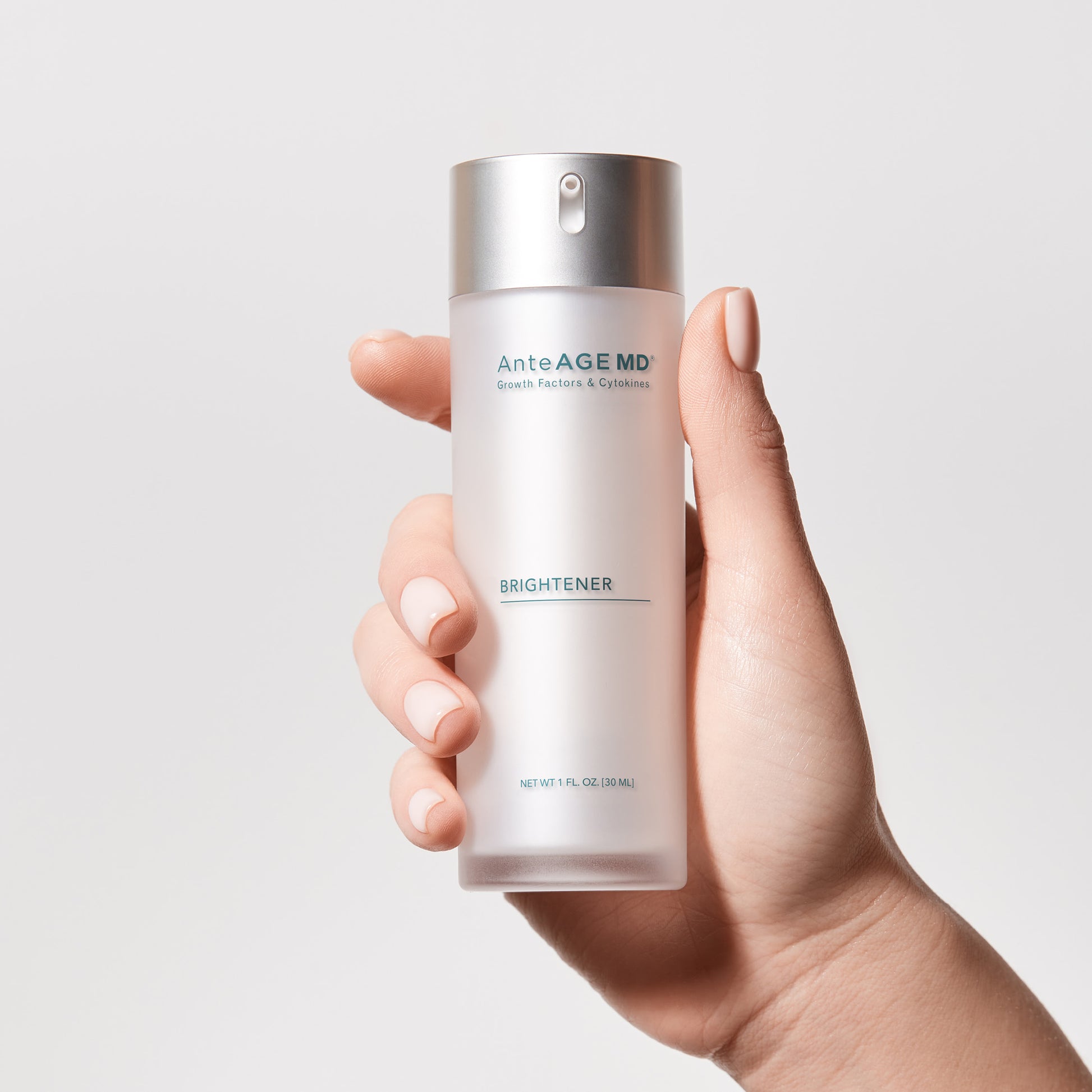 Hand holding a bottle of AnteAGE MD Brightener against a light gray background