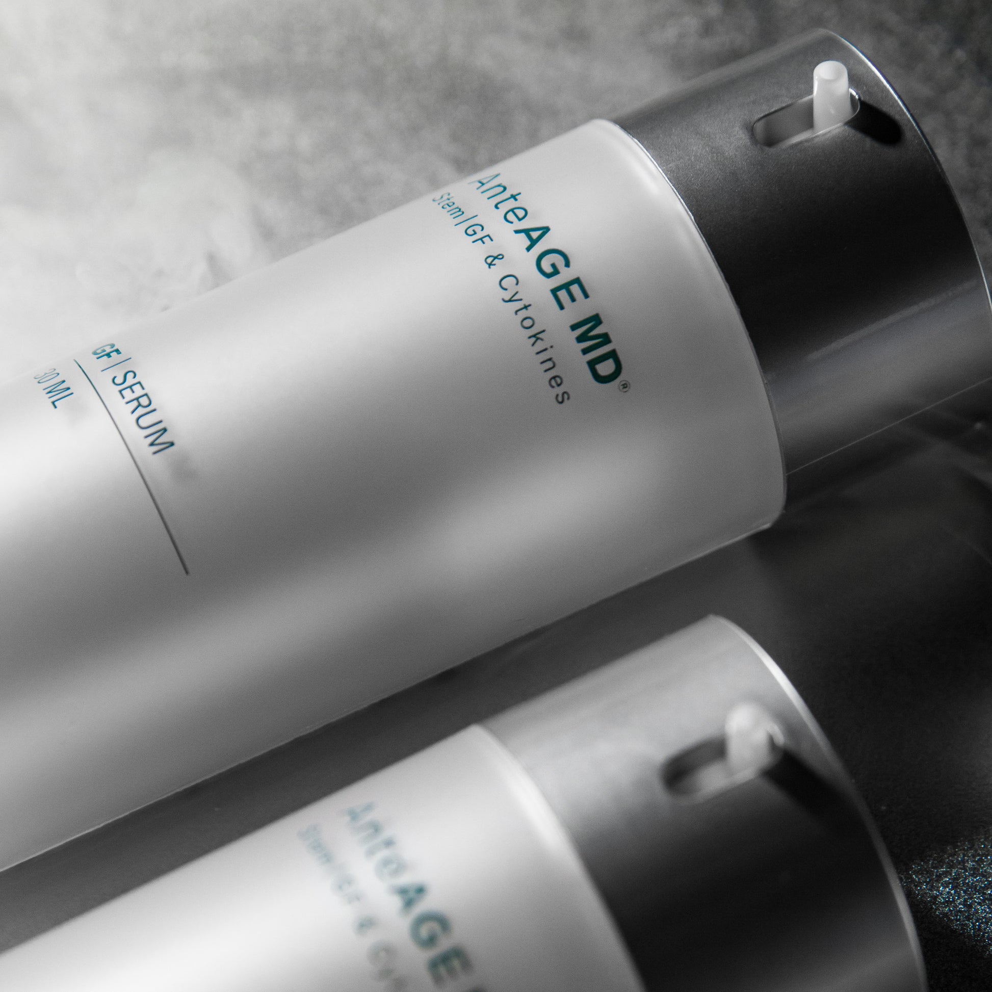 Two skincare bottles labeled 'AnteAGE MD' on a textured surface.