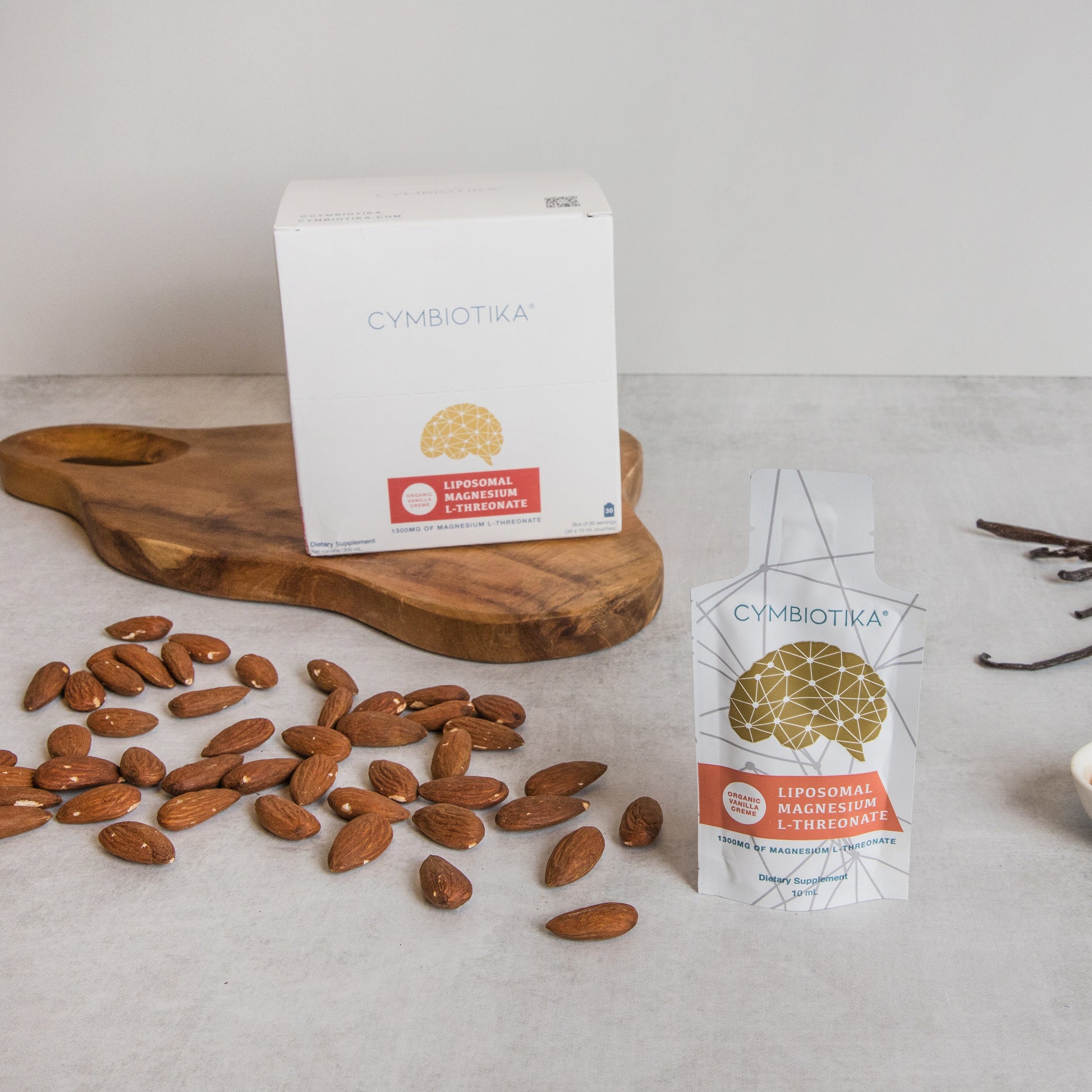 Cymbiotika supplement boxes with almonds on a light surface