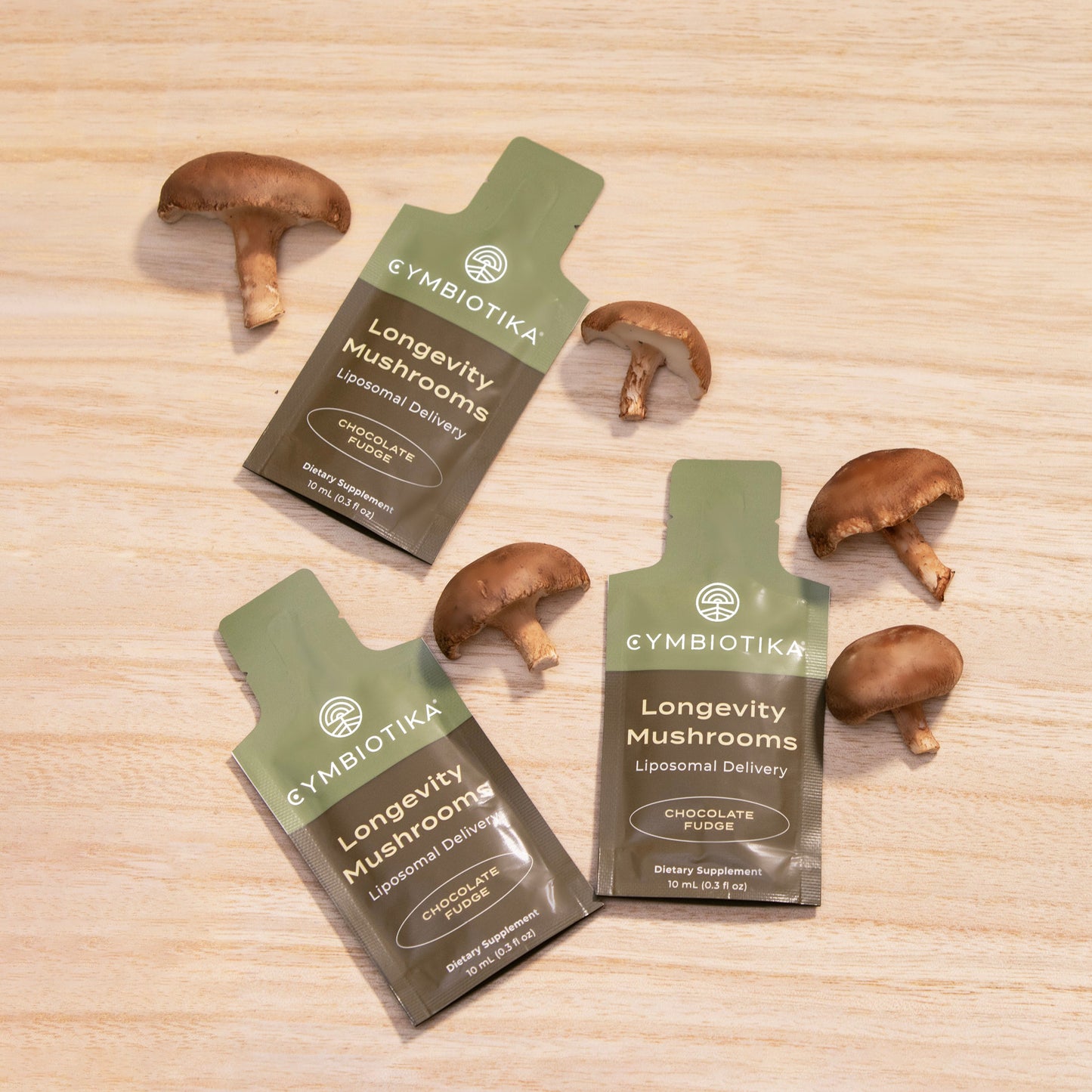 Cymbiotika Longevity Mushrooms packages on a wooden surface with mushrooms around.