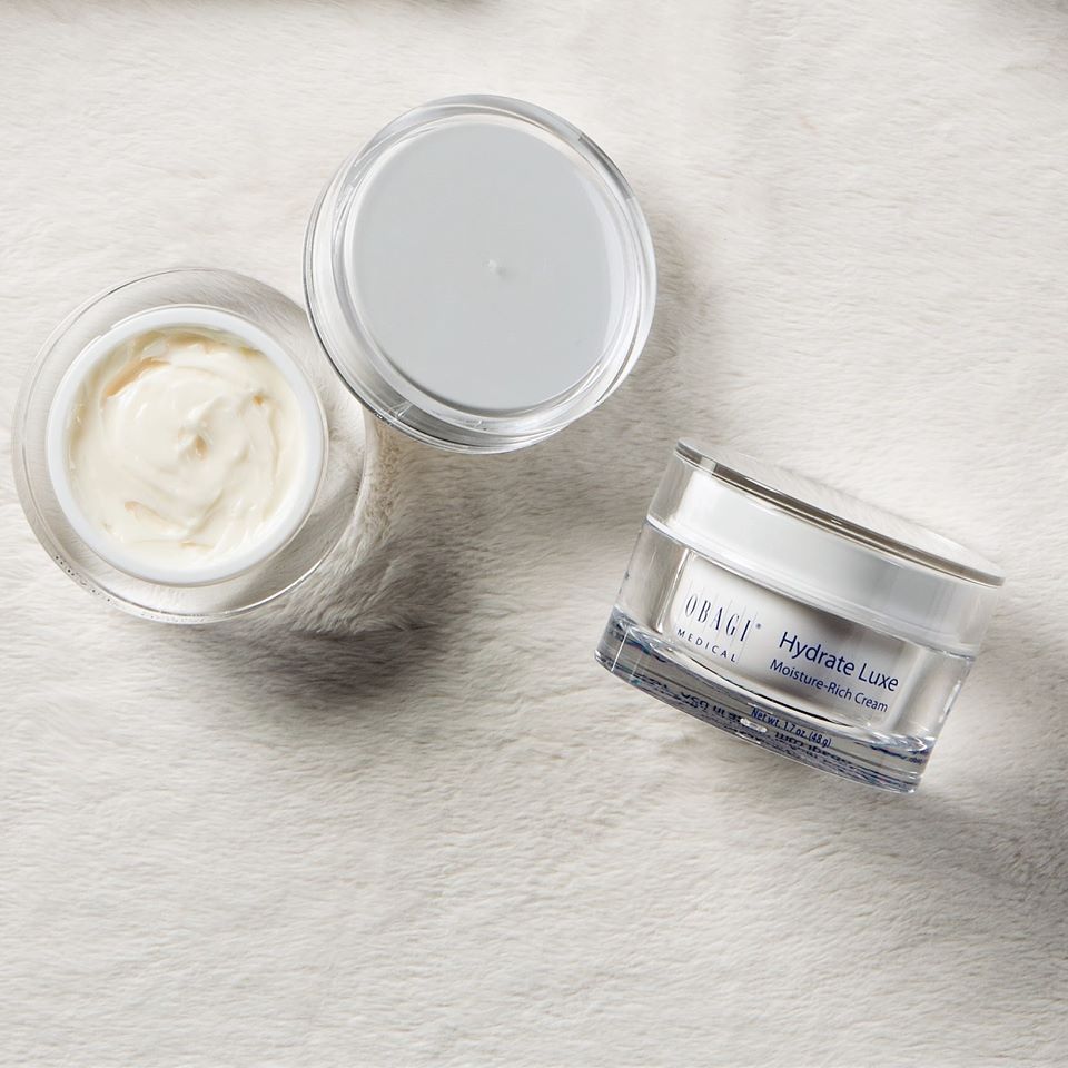 Three jars of skincare cream on a textured surface Hyrdate Luxe