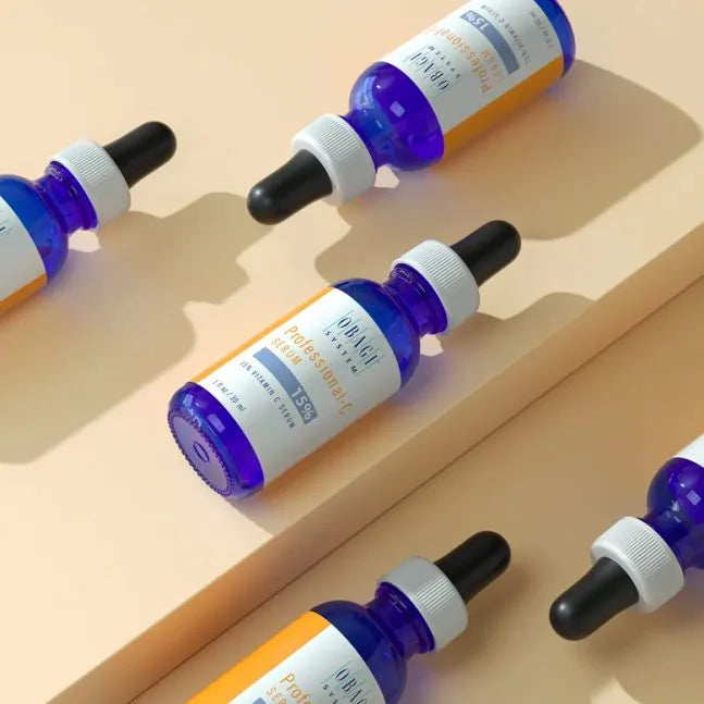 Multiple bottles of a skincare product with droppers on a beige background