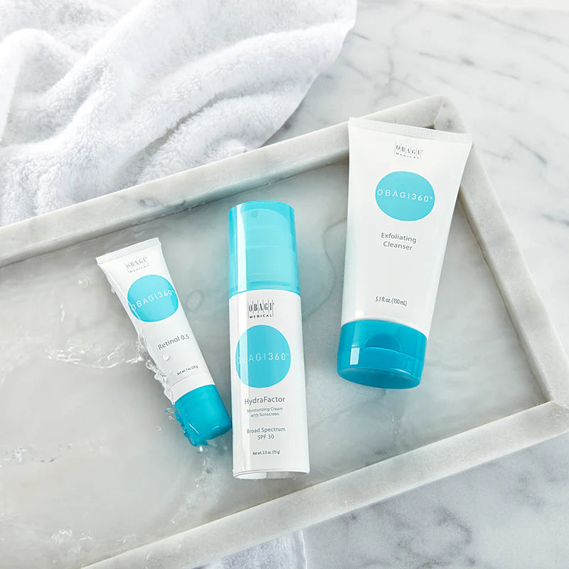 Three skincare products with blue and white packaging on a marble surface