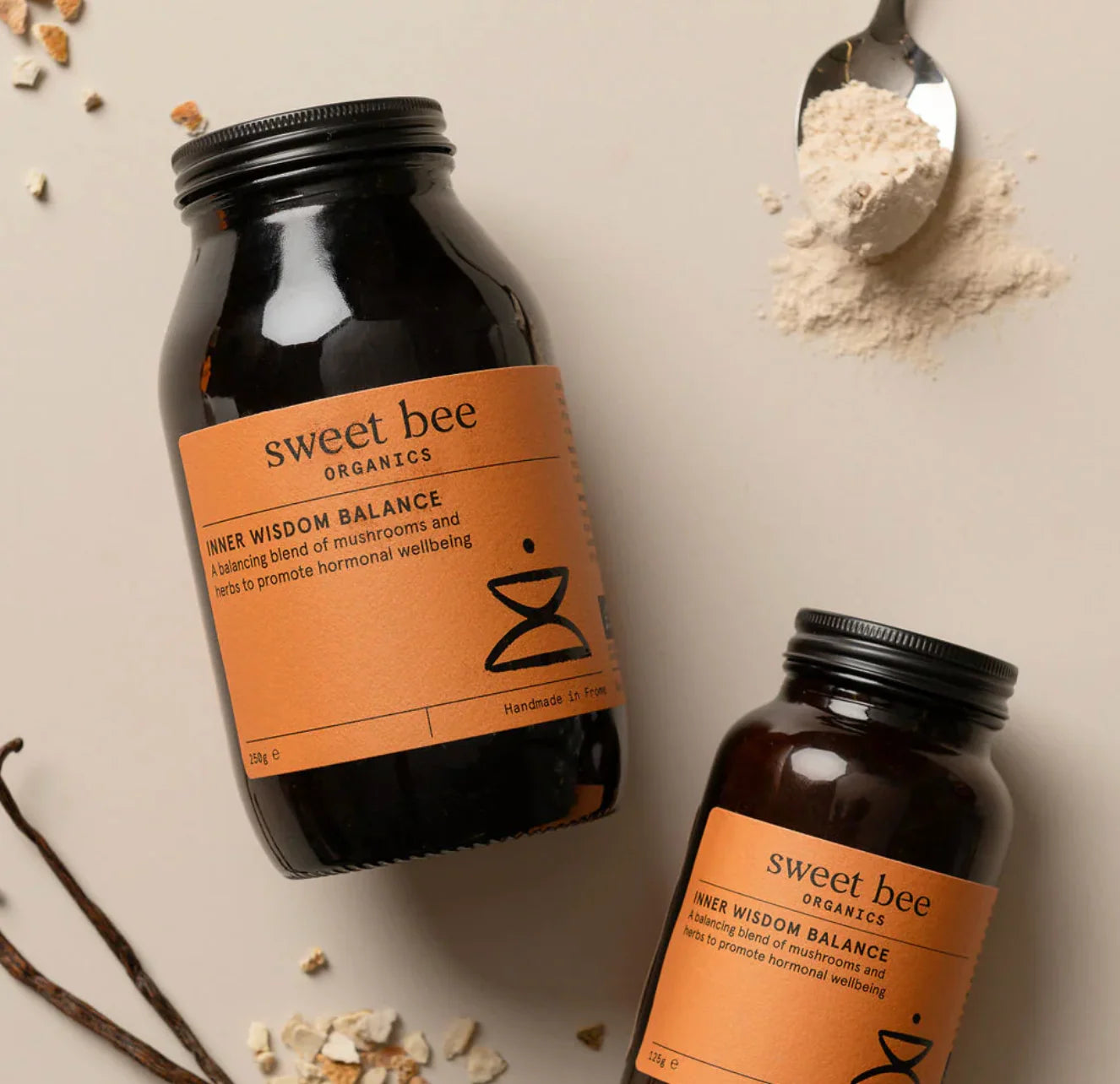 Two bottles of 'sweet bee' Organics on a neutral background with ingredients around.