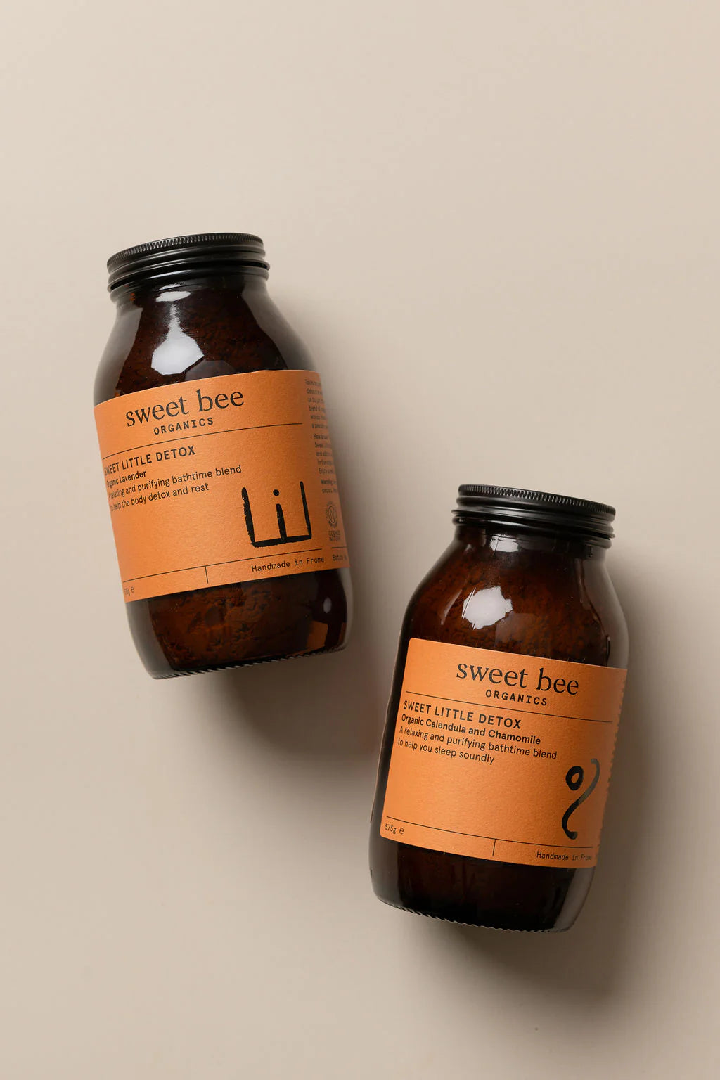 Two bottles of 'sweet bee' products on a beige background