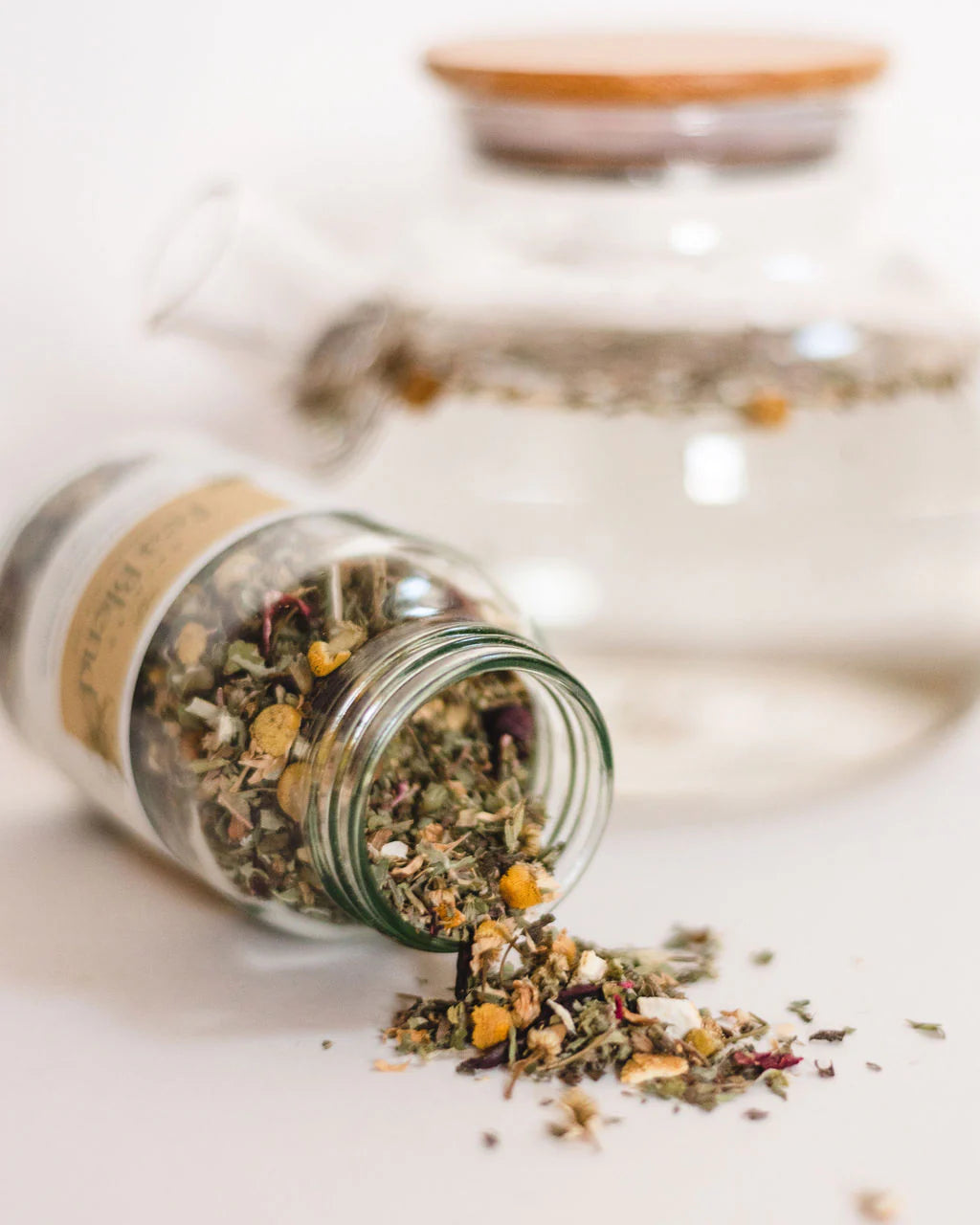 Glass jar of dried herbs on a white surface