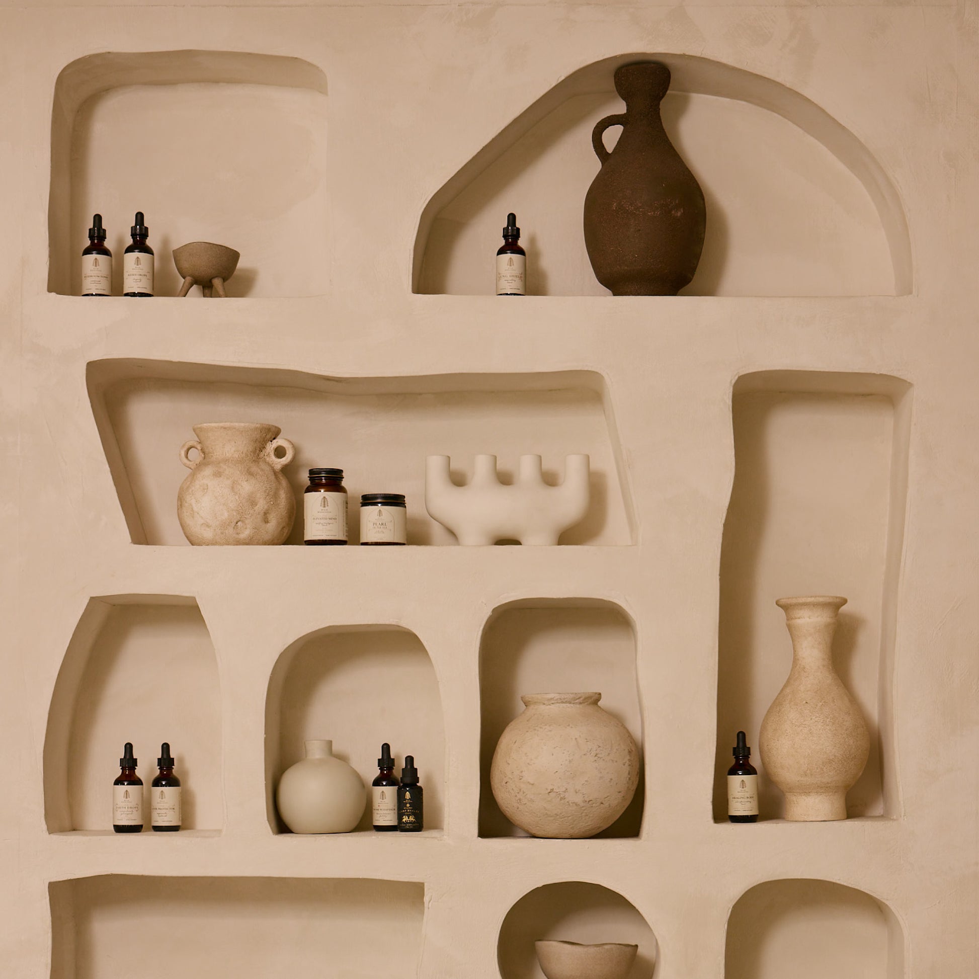 Beige shelves with ceramic vases and bottles against a beige wall