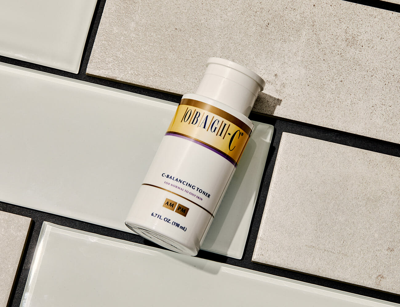 Skincare bottle labeled 'JOBAUGH-C' on a tiled surface