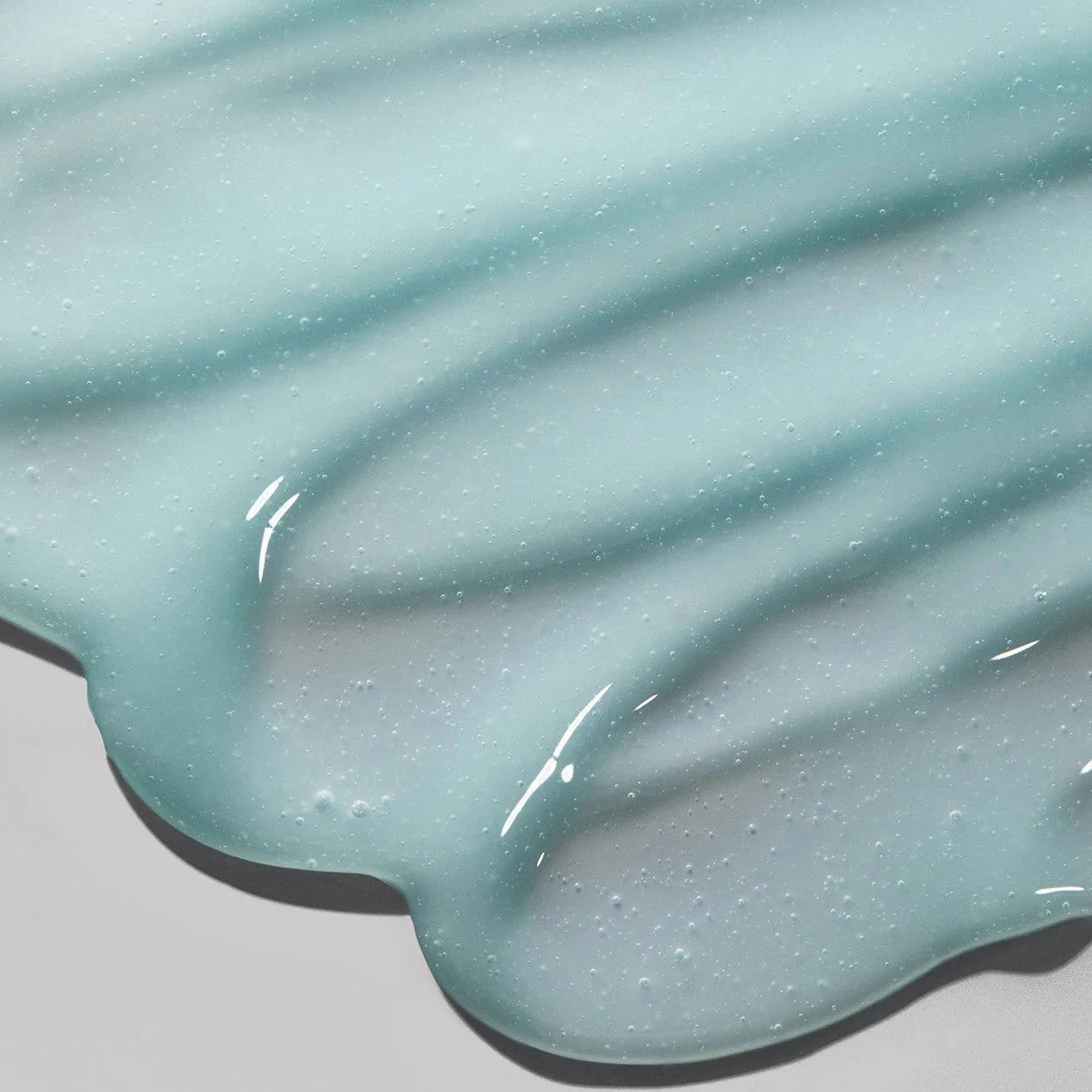Close-up of a light blue, glossy substance on a gray background
