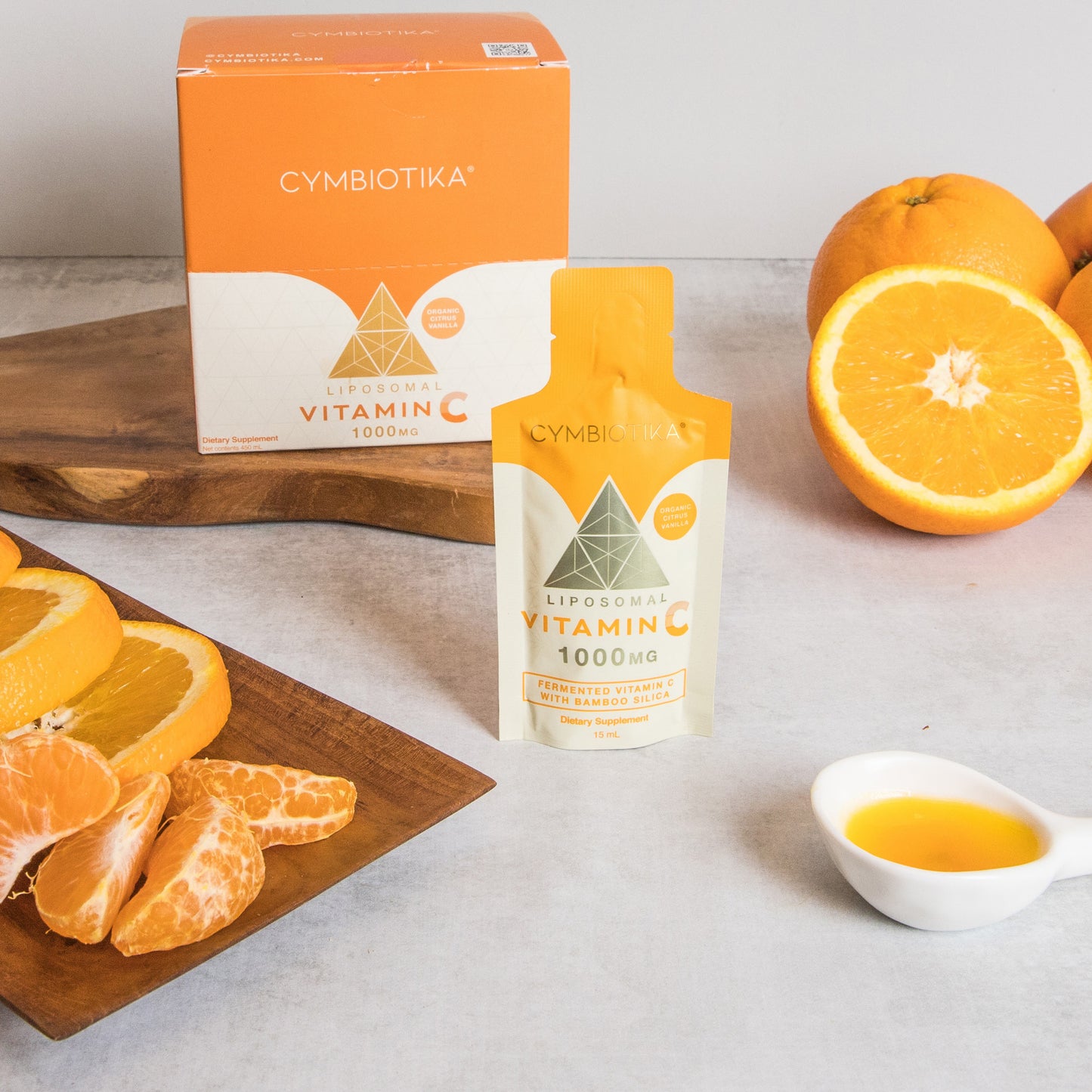 Cymbiotika Vitamin C supplement bottle and packaging with oranges on a table