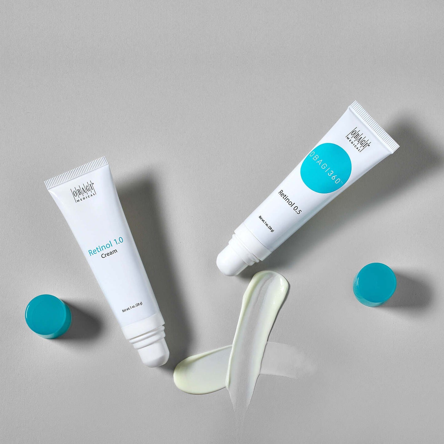 Two tubes of cream with a swatch of cream on a gray background