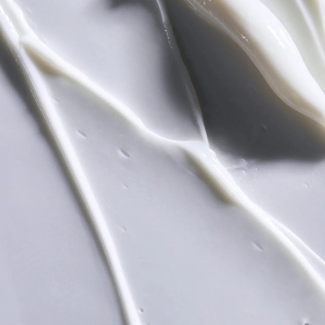 Close-up of white cream or paint on a gray background